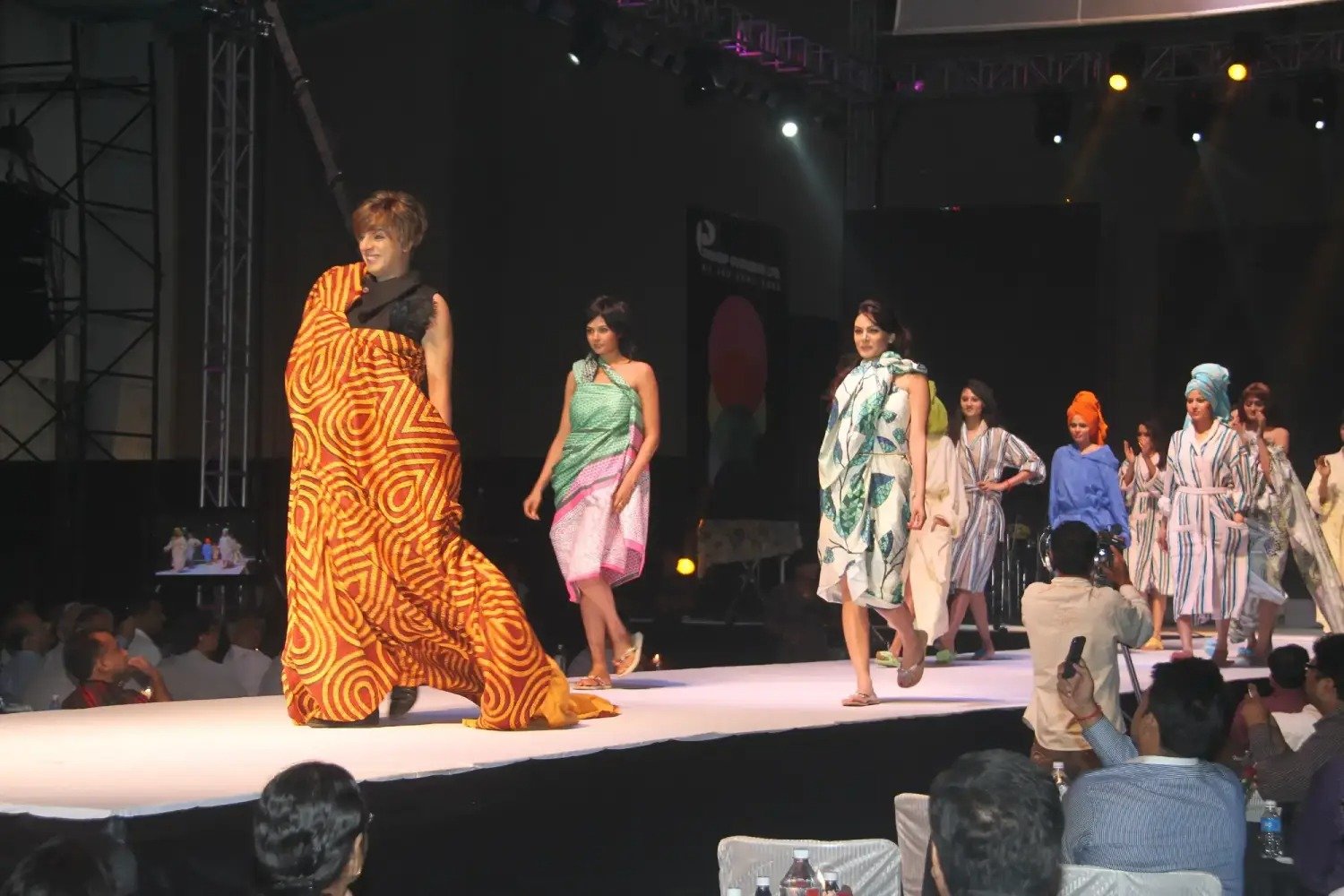 Man and woman speaking on stage at night with blue lighting